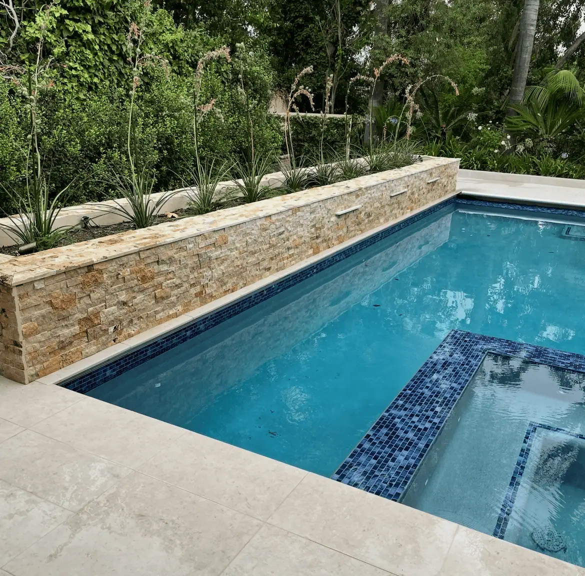 Pool with stone wall and landscaping for outdoor luxury.